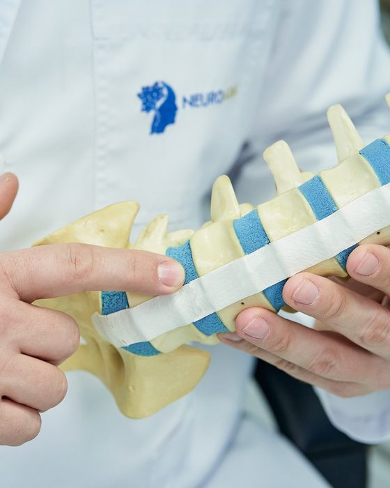 Explicación de una patología sobre un modelo anatómico de columna lumbar.